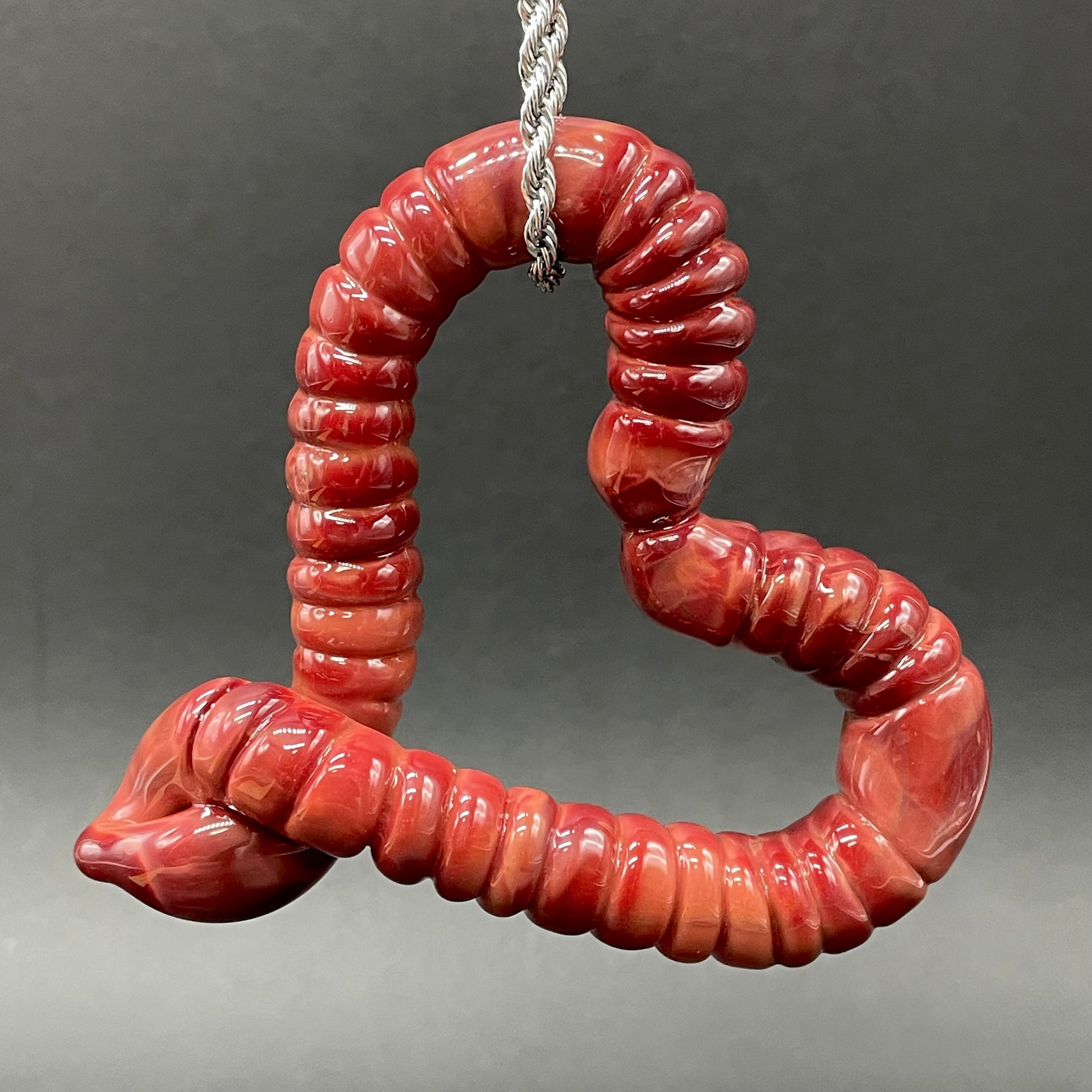 Close-up of Large glass earthworm heart shaped pendant - handcrafted glass
